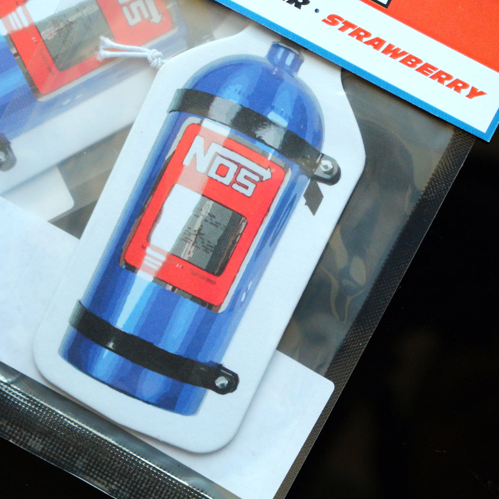 This NOS Bottle air freshener strawberry provides a sweet and fruity aroma to uplift your spirits. Each air freshener comes sealed and includes an elastic tie for easy placement.