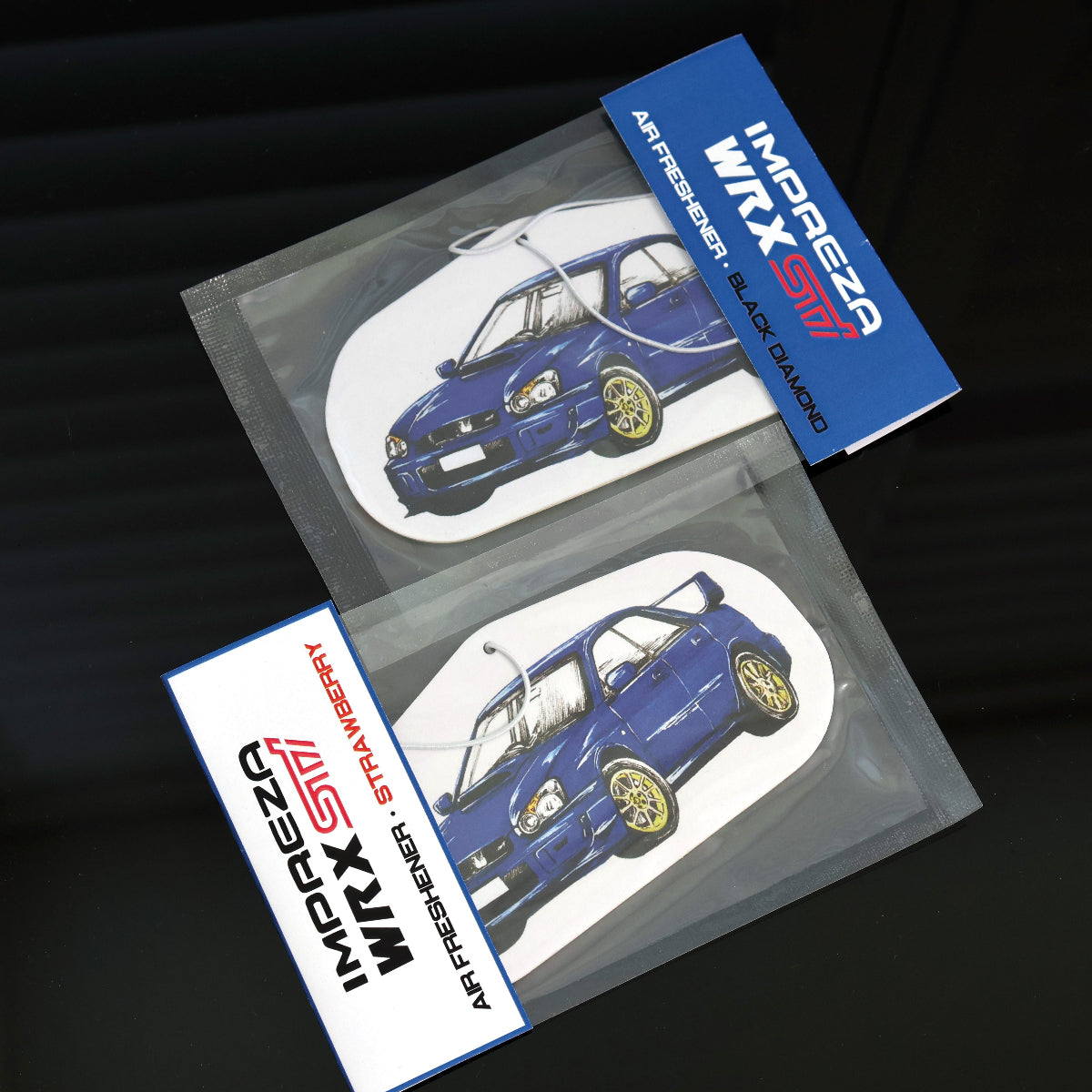 Individually packaged WRX Sti air freshener with elastic tie, available in black diamond and strawberry scents