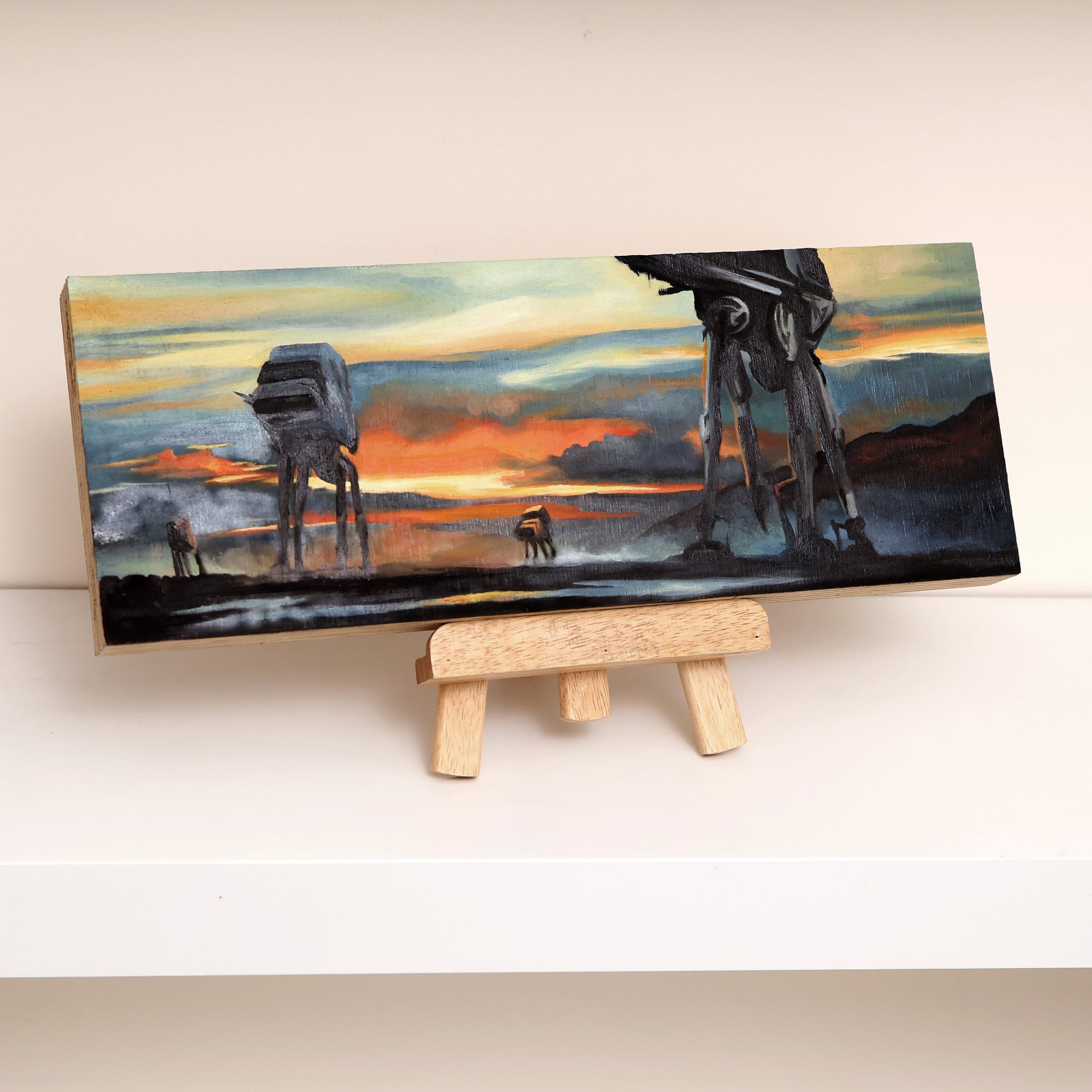 Original oil painting on wood panel depicting silhouetted AT-AT walkers from Star Wars marching across a misty landscape at sunset. Vivid orange, yellow, and blue tones create a dramatic sci-fi atmosphere, with bold contrast and cinematic composition on easel.