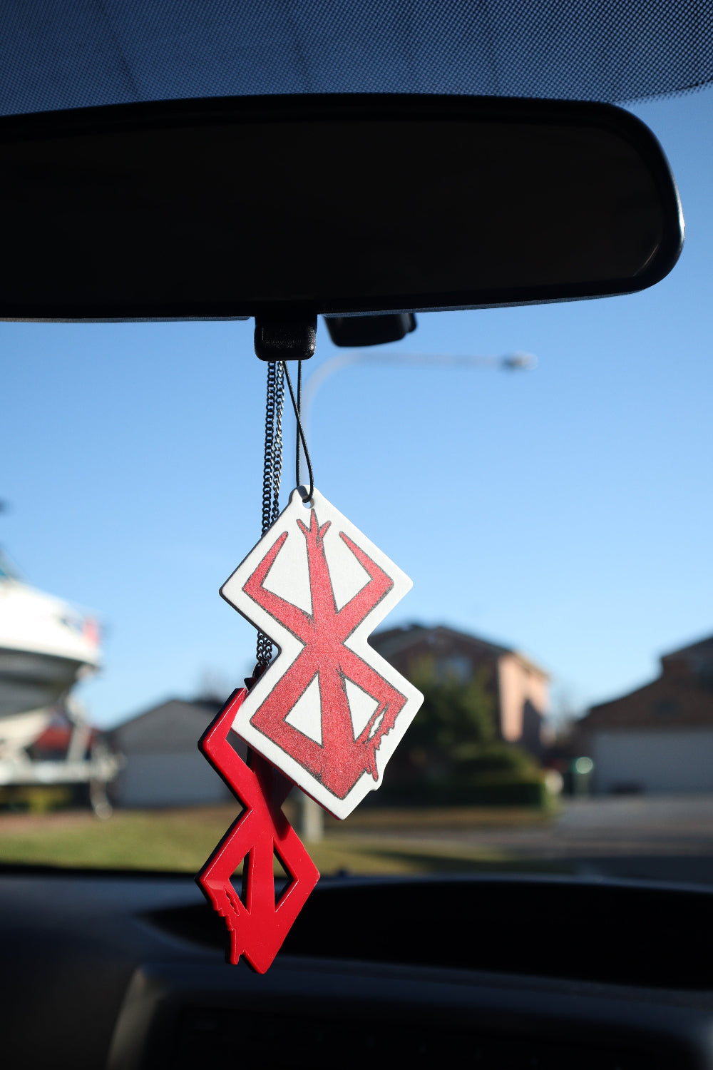 Showing a pair of Berserk Brand of scarifice air freshener and keychain hanging from the rear-view mirror.