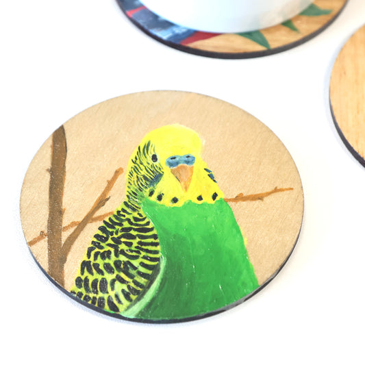 Original Australian art. Hand painted, green-yellow colour budgerigar on wooden coaster. Left side view of head and front half body. Original Australian bird artwork from Artysn Studio.