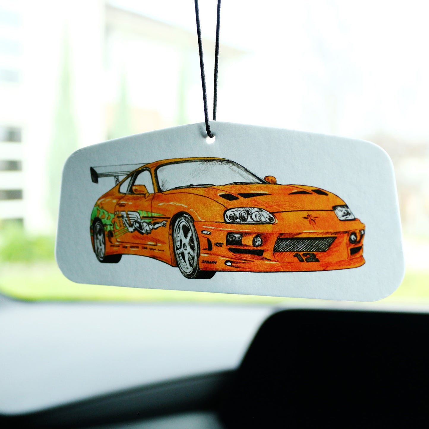Brian’s MK4 Supra air freshener hanging inside a car interior, orange Supra design.