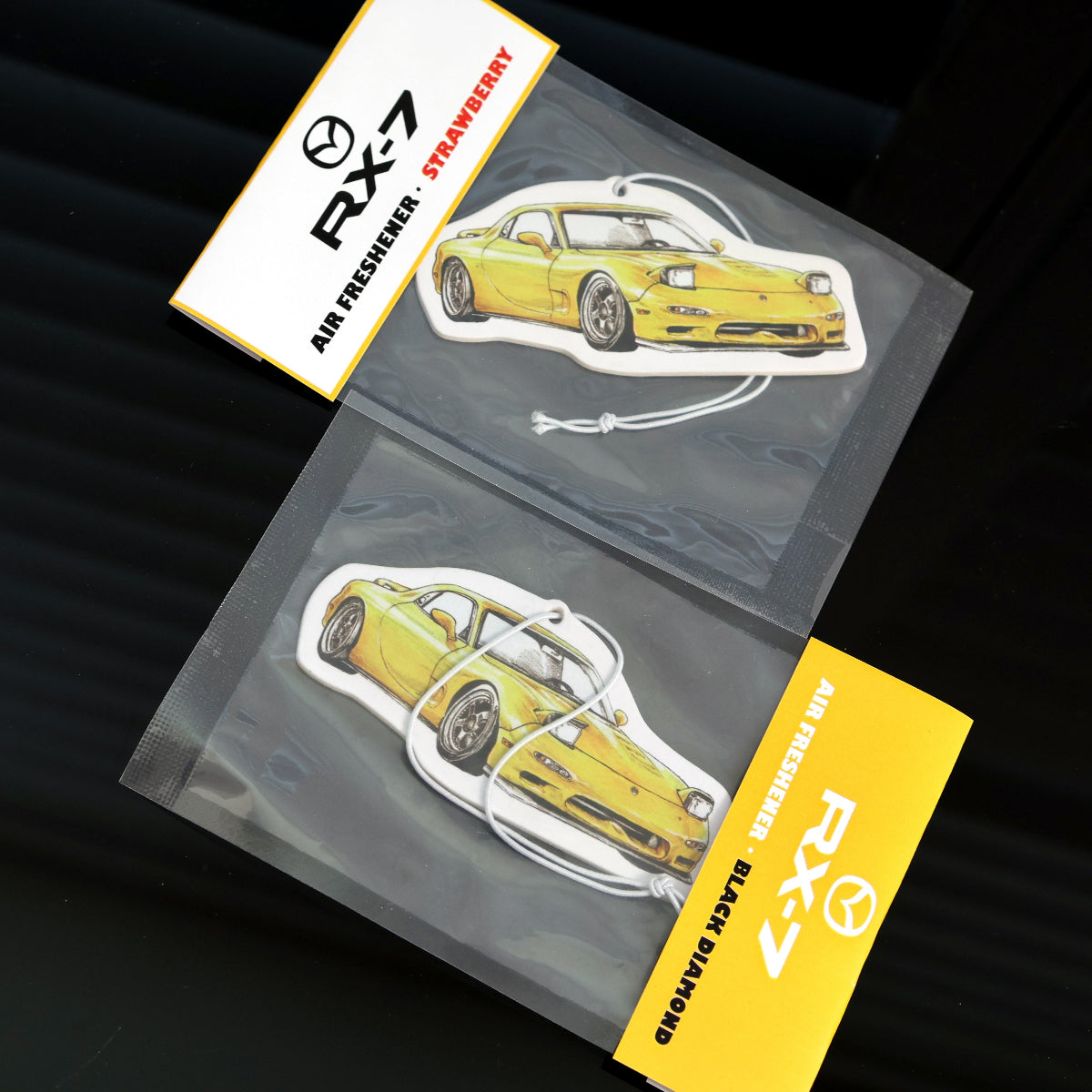 Individually sealed RX-7 air freshener with elastic tie, available in strawberry and black diamond scents