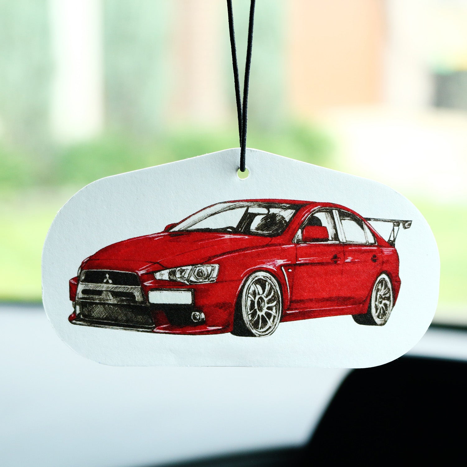 Red Mitsubishi Lancer EVO X air freshener hanging inside a car interior.