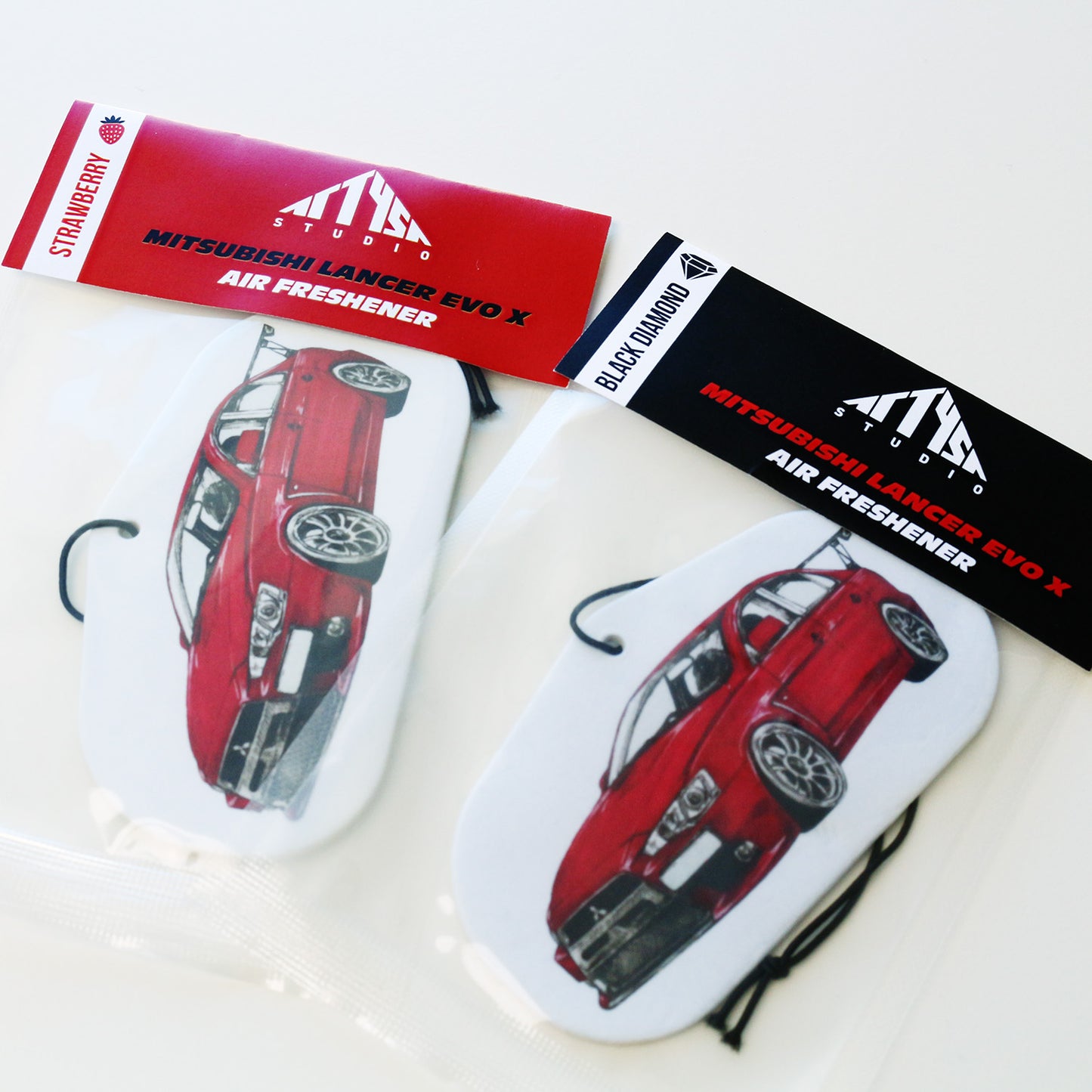 Packaged Mitsubishi Lancer EVO X air freshener with hand‑drawn JDM artwork and elastic tie.