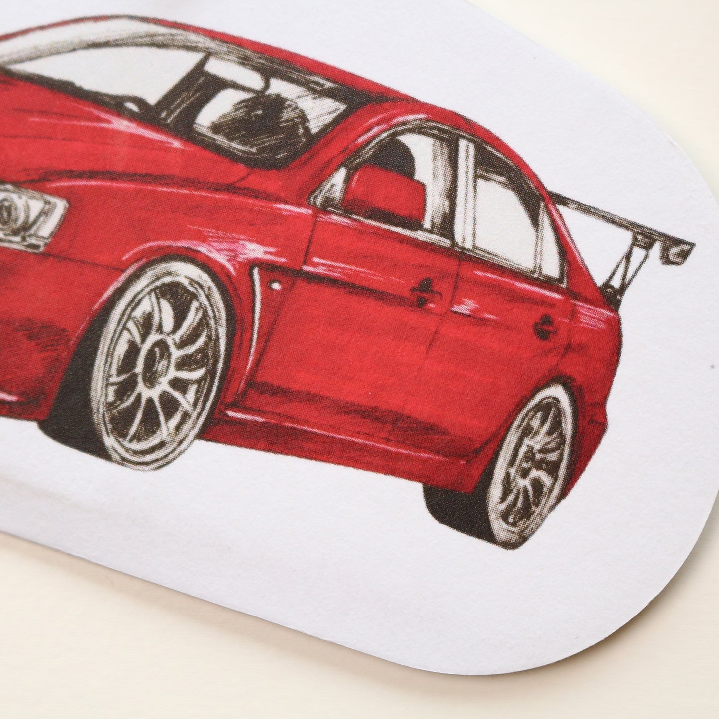 Close‑up of red body and rear end of Mitsubishi Lancer EVO X air freshener showing detailed hand‑drawn artwork.