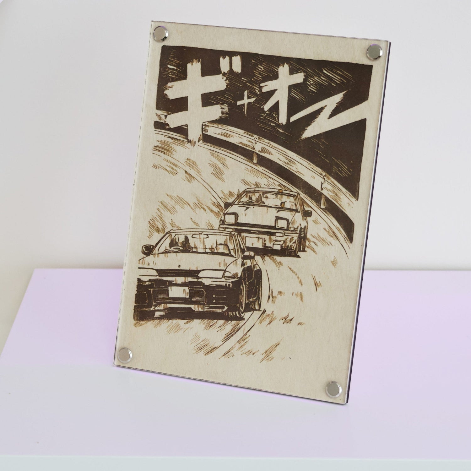 JDM car culture artwork created with LayaBoard Art system. This picture showing a laser engraved artwork of GTR R32 racing AE86 in manga style on a desk.