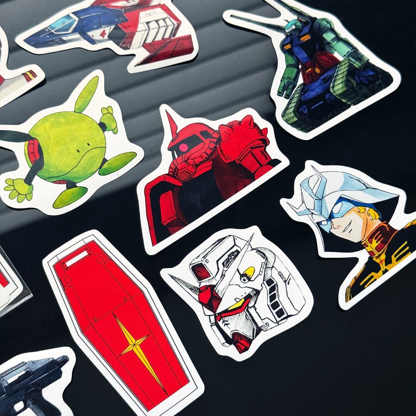 Close-up of hand‑drawn Gundam sticker pack showcasing classic mobile suit icons.