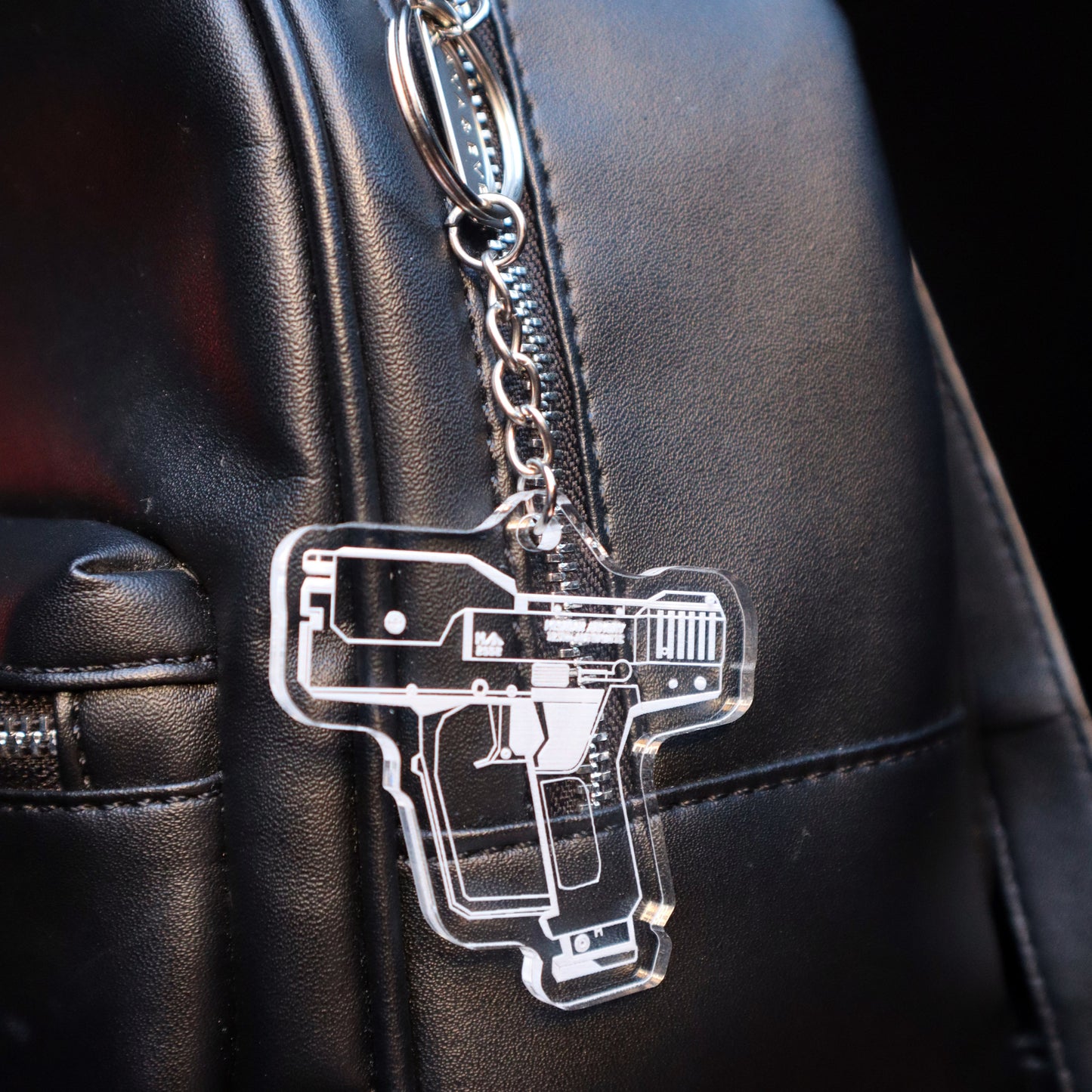Halo Magnum Pistol acrylic keychain attached to carry bag, gaming merch accessory, unisex fandom gift.