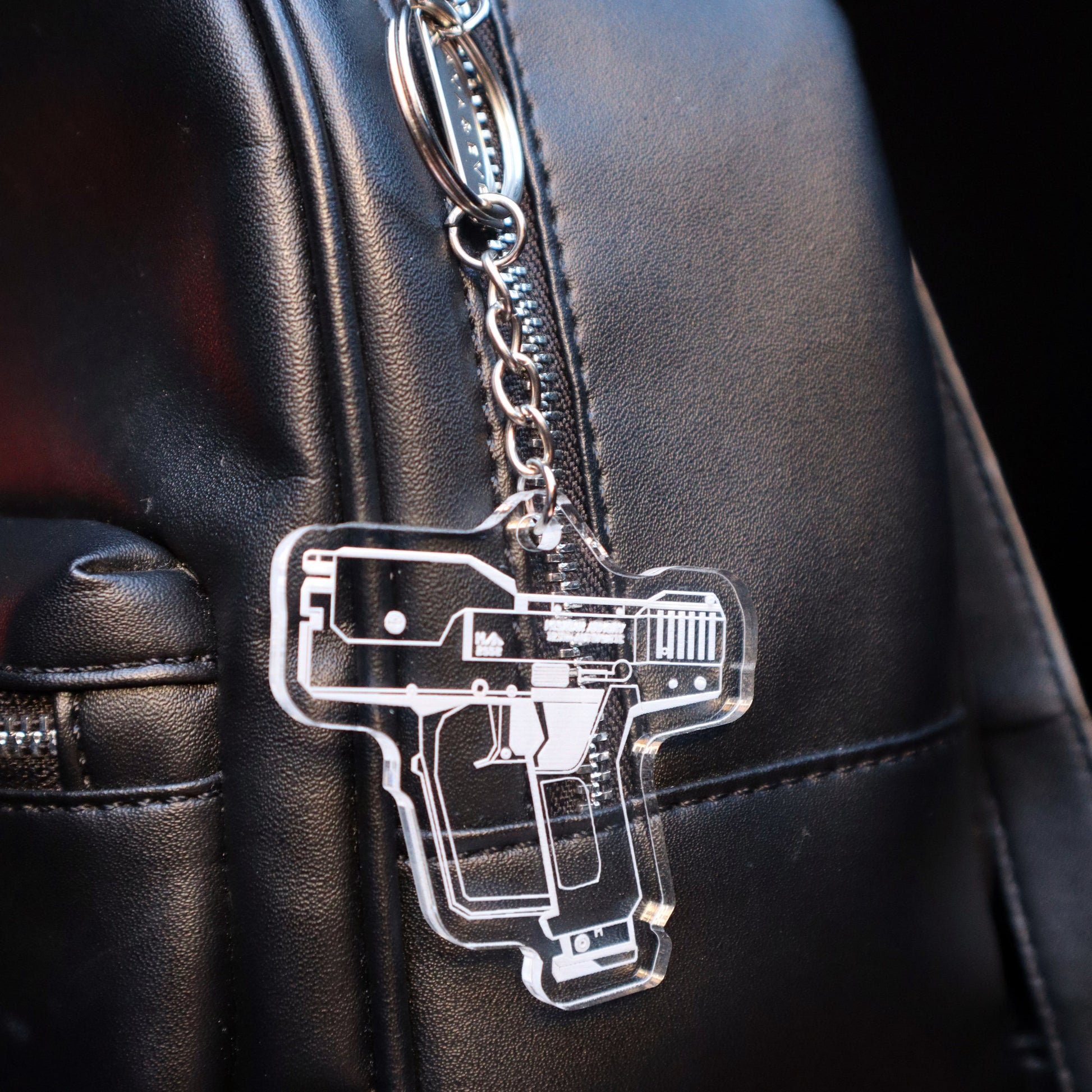 Halo Magnum Pistol acrylic keychain attached to carry bag, gaming merch accessory, unisex fandom gift.