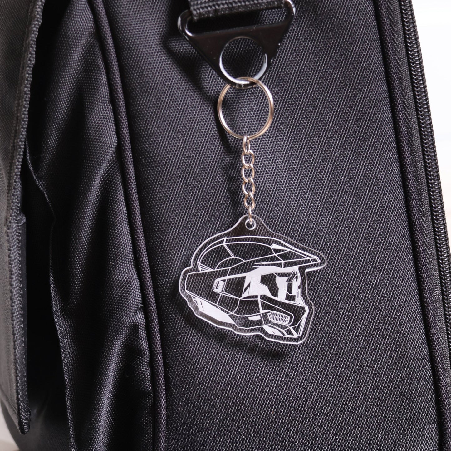 Halo Master Chief Helmet Mark VI keychain made from clear acrylic attached to a black bag
