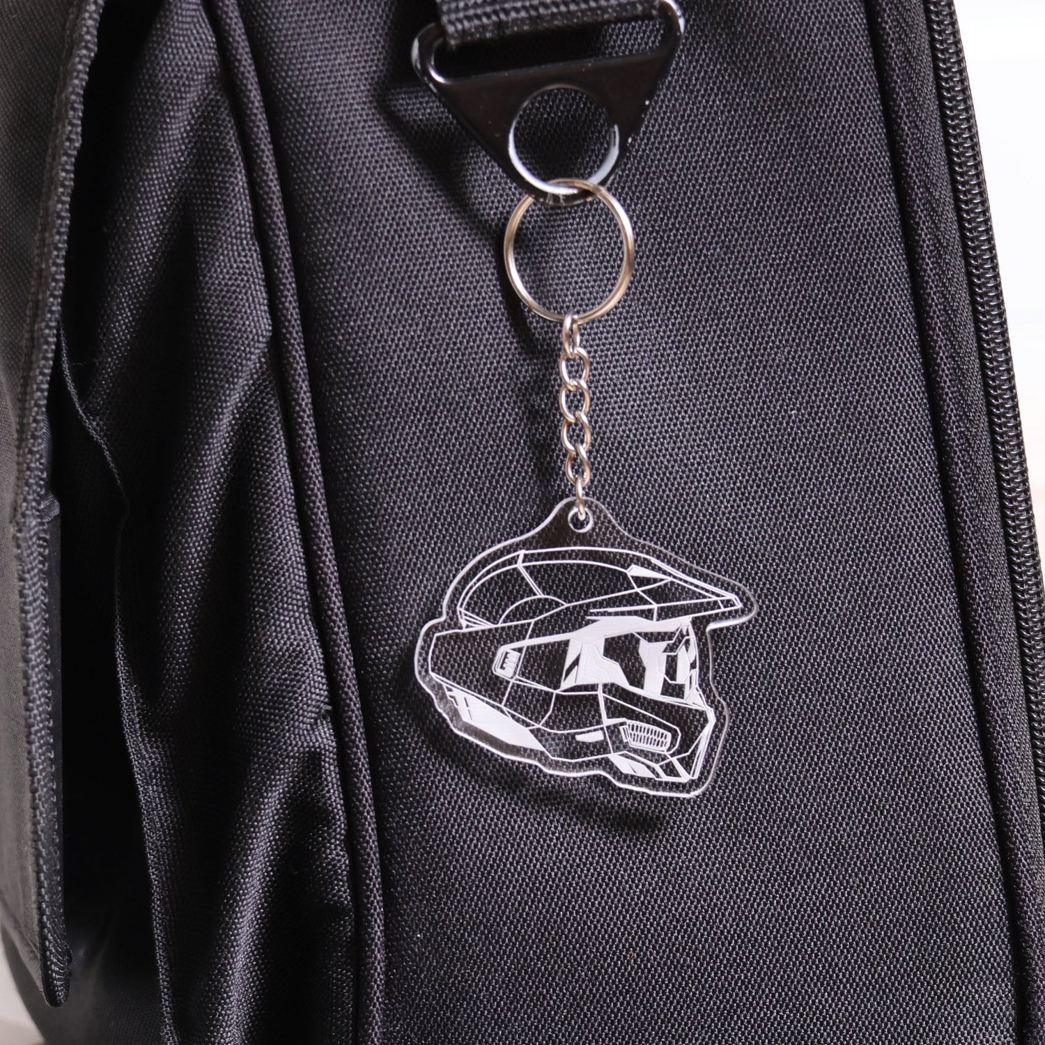 Halo Master Chief Helmet Mark VI keychain made from clear acrylic attached to a black bag