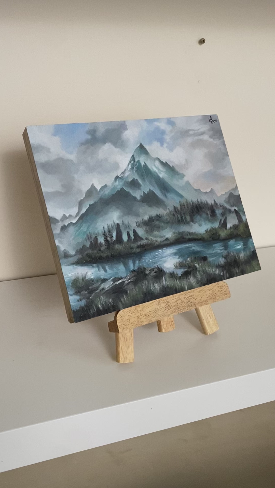 Video showing details of original oil painting on wood panel depicting the Throat of the World from Skyrim. Features a snow-covered mountain peak rising into a cloudy sky, surrounded by misty ridges and a reflective lake in the foreground. Soft blues, whites, and greens create a tranquil, atmospheric fantasy landscape.