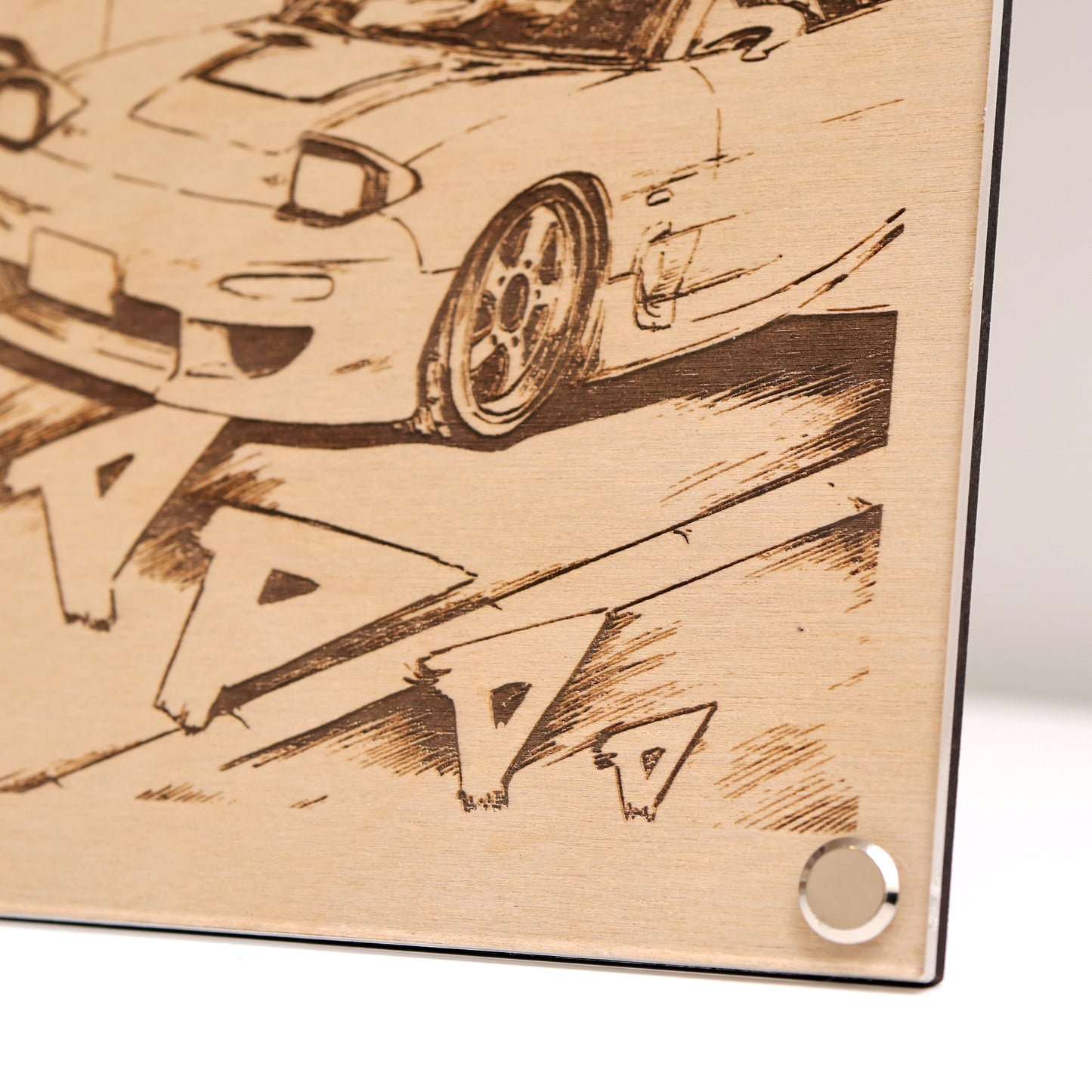 Bottom right corner close-up of wooden plaque with laser-engraved design of 2x RX-7 and Japanese text.