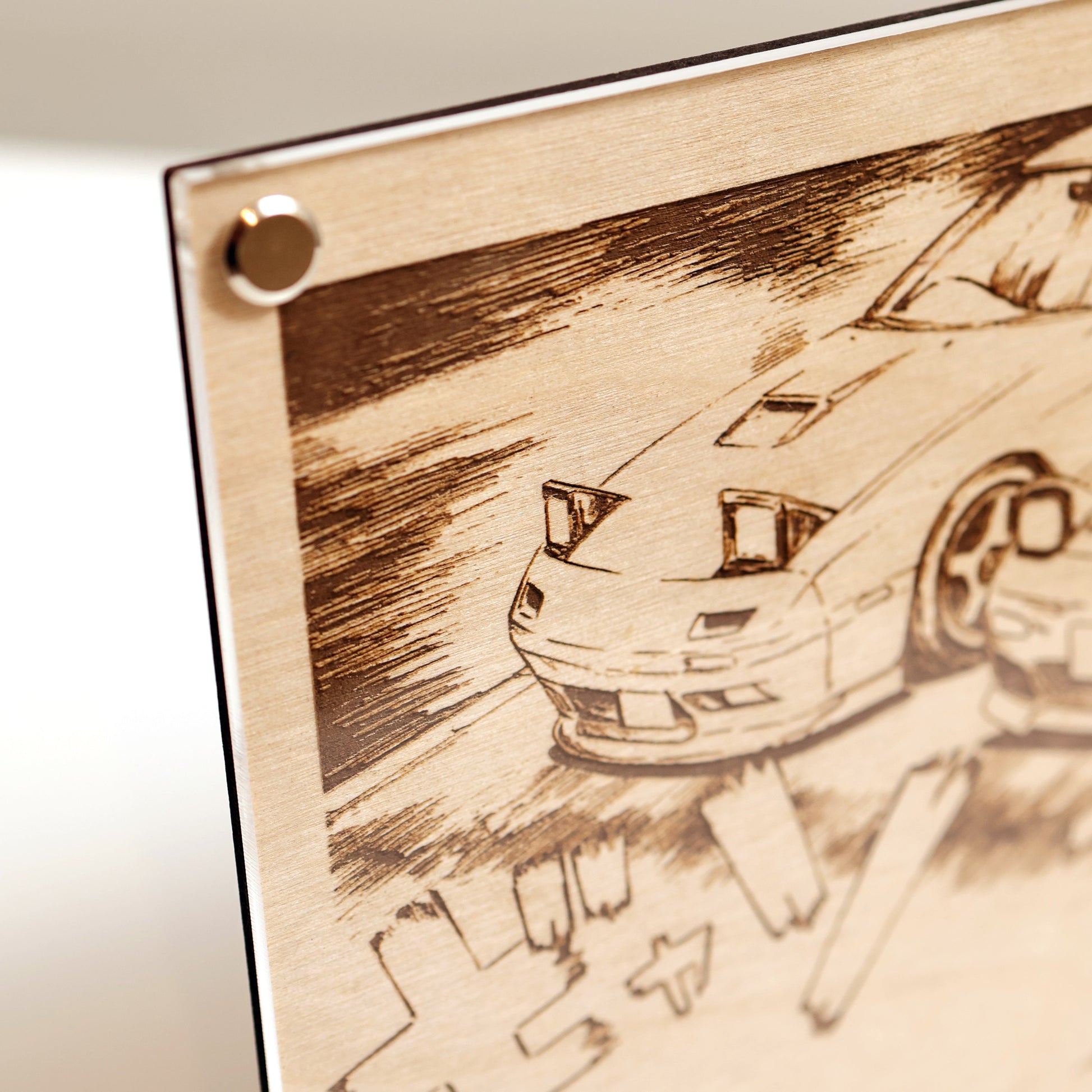 Top left corner close-up of wooden plaque with laser-engraved design of 2x RX-7 and Japanese text on a white background