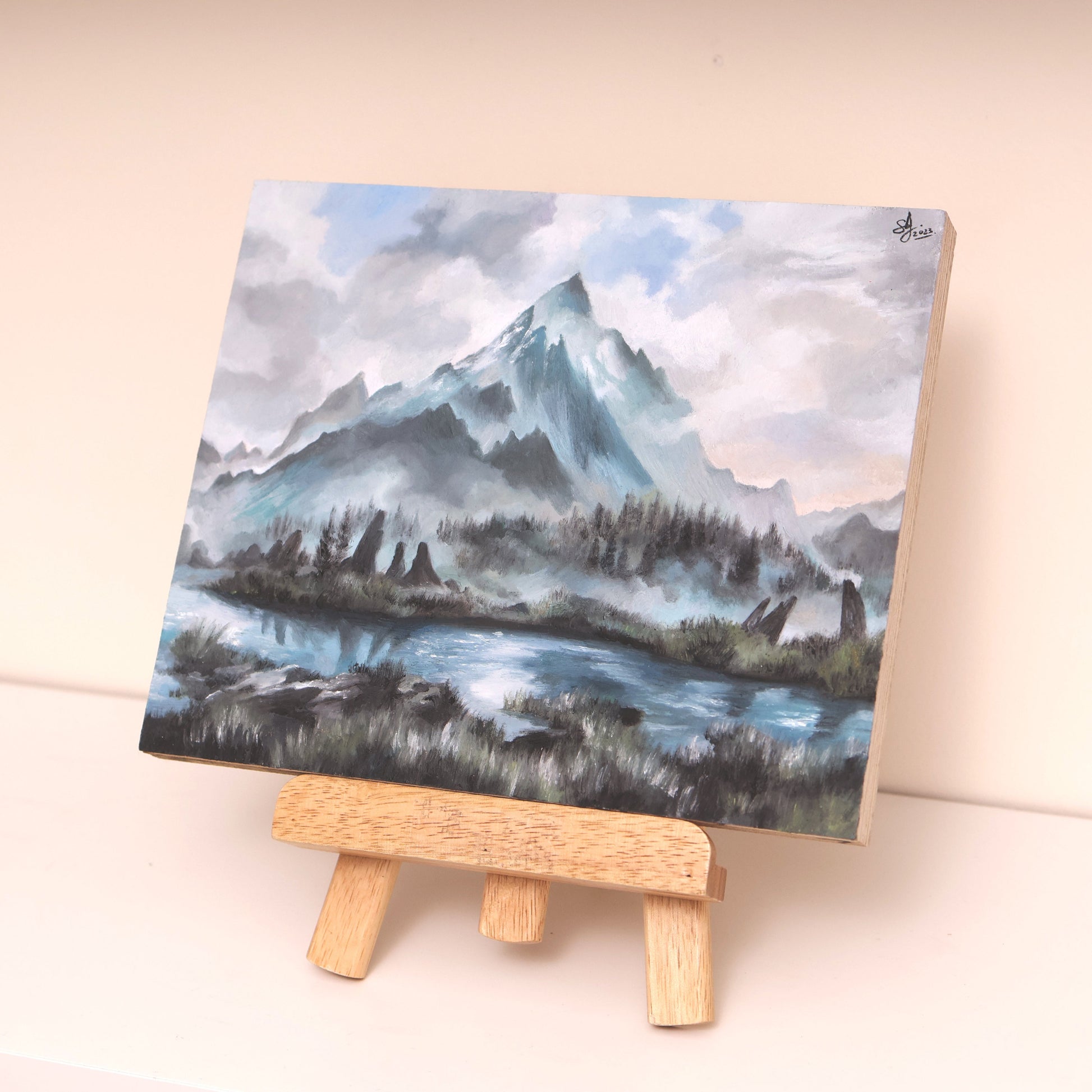 Original oil painting on wood panel displayed on easel, depicting the Throat of the World from Skyrim. Features a snow-covered mountain peak rising into a cloudy sky, surrounded by misty ridges and a reflective lake in the foreground. Soft blues, whites, and greens create a tranquil, atmospheric fantasy landscape.